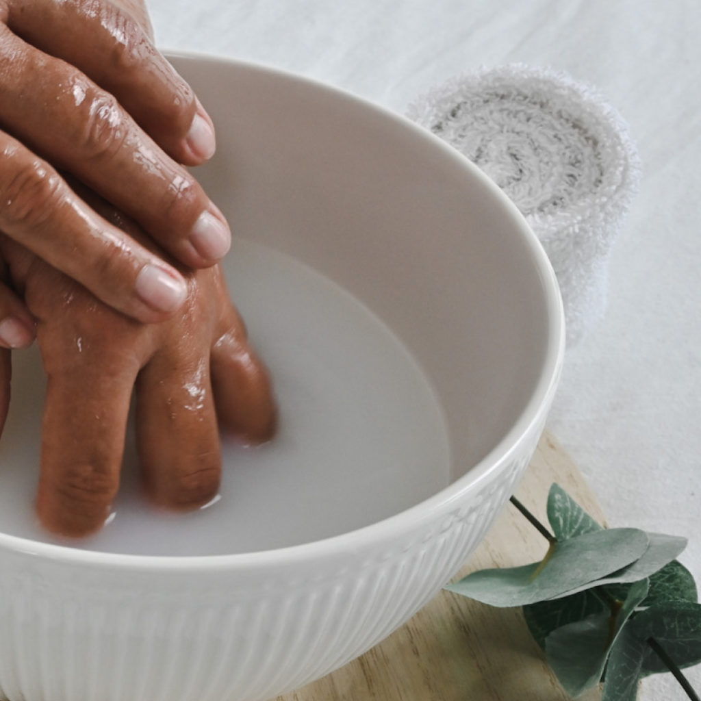 Wasserschale mit Händen und Handtuchrolle